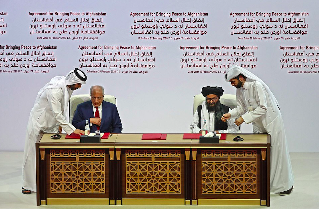 Zalmay Khalilzad and Mullah Baradar sign the US-Taliban peace agreement in the Qatari capital Doha. Credit to AFP via Getty Images