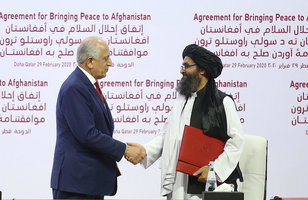 Zalmay Khalilzad (L) and Mullah Baradar (R) shake hands after signing a peace agreement between Taliban and US officials in Doha, Qatar, 29 February 2020. Credit to Anadolu Agency via Getty Images
