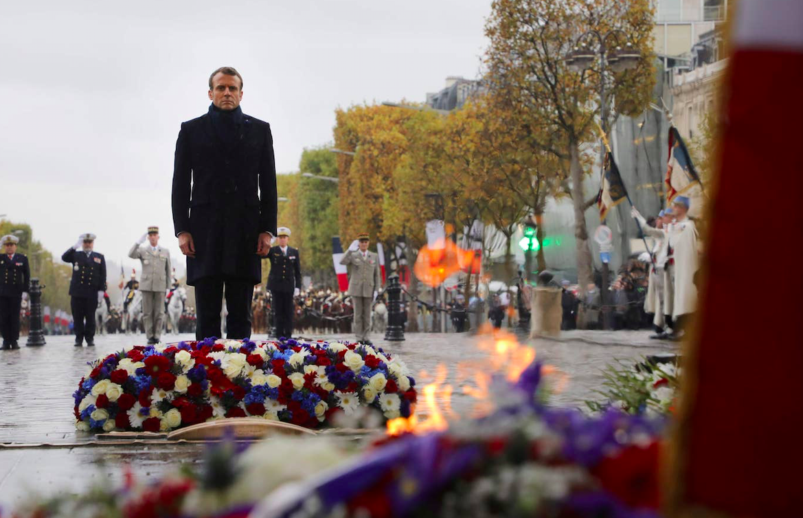 French President Emmanuel Macron stands by a wreath of flowers during a ceremony at the Arc de Triomphe in Paris 2019. Credit: POOL/AFP via Getty Images