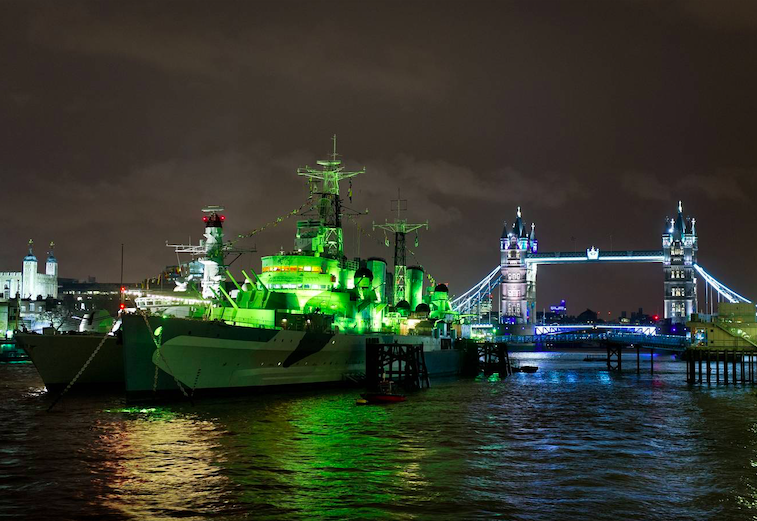 HMS Belfast is lit green on the River Thames. Credit: PA Archive/PA Images