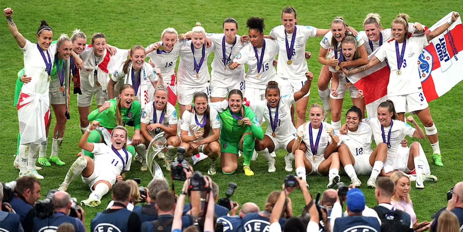The England team celebrate with the trophy in front of the row of photographers. Credit to AP