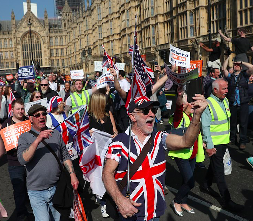 The man in a Union flag shirt holds an American flag over his shoulder as the Brexiteer group march down towards the media area at College Green. Credit: The Daily Mail/AFP/Getty Images