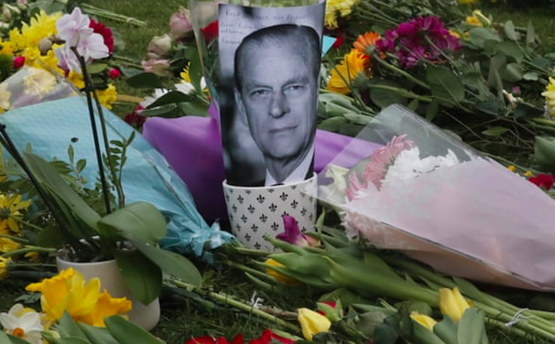 A photo of Britain’s Prince Philip is among flowers left by the public outside the gates of Windsor Castle in Windsor, England. Credit to Frank Augstein/AP