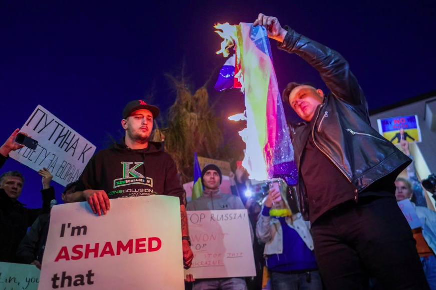 A member of the Russian-American community burns a Russian flag during a demonstration in support of Ukraine in Los Angeles, California. Credit to The New York Post/Reuters