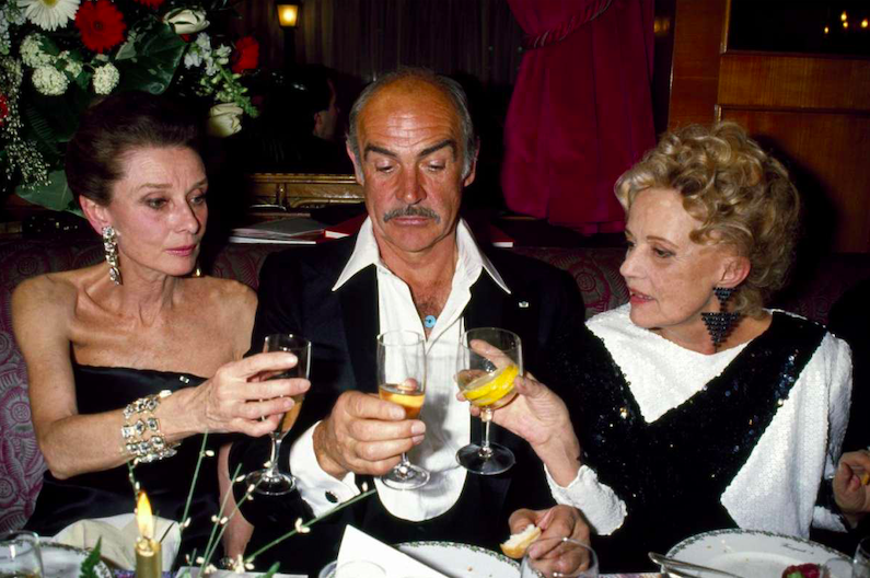 Audrey Hepburn, Sean Connery and Jeanne Moreau (L-R) at Fouquet's, a historic high-end brasserie restaurant at 99 Avenue des Champs-Élysées, in 1991 (Paris, France)